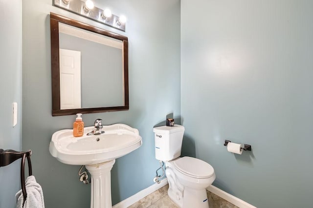 half bath featuring tile patterned flooring, baseboards, and toilet