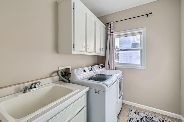 laundry room with baseboards, cabinet space, a sink, and washing machine and clothes dryer