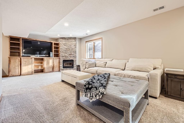 living area featuring recessed lighting, visible vents, light carpet, a stone fireplace, and a textured ceiling