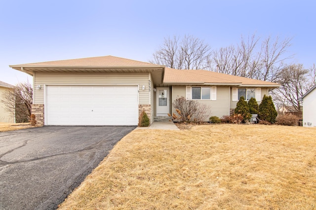 single story home with an attached garage, a front lawn, aphalt driveway, and brick siding