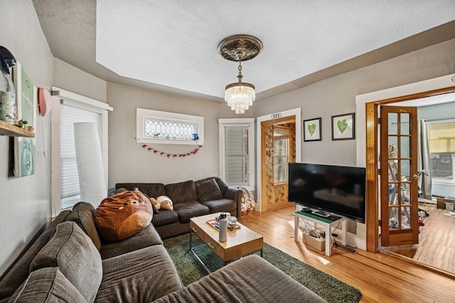 living area featuring baseboards, a textured ceiling, an inviting chandelier, and wood finished floors