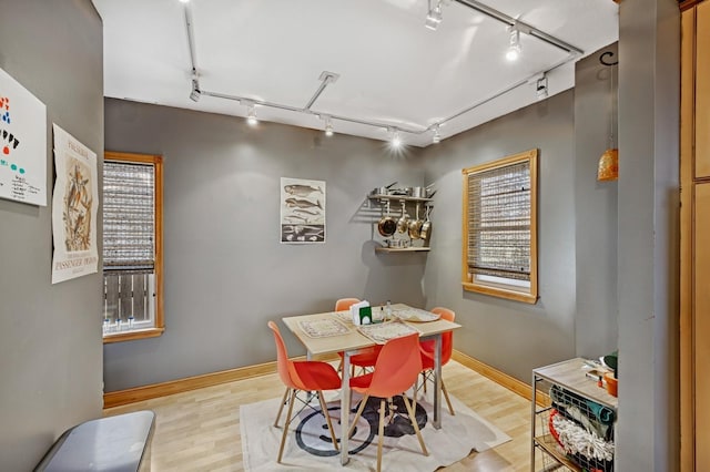 dining space featuring baseboards, wood finished floors, and track lighting