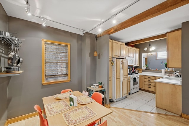 kitchen featuring white appliances, a sink, light countertops, light wood-type flooring, and light brown cabinetry