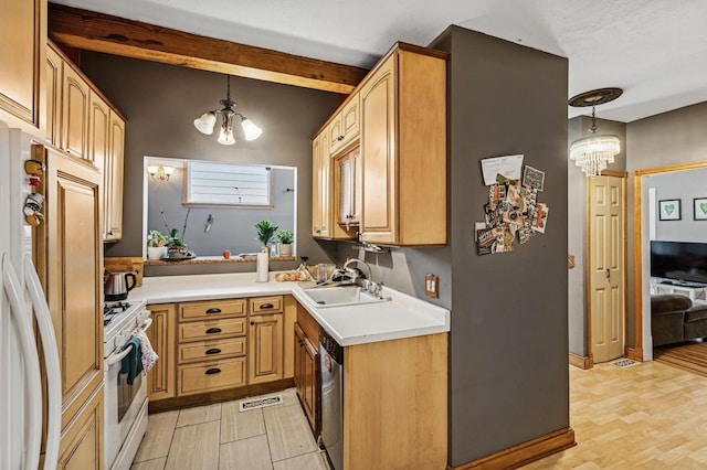 kitchen featuring a notable chandelier, built in fridge, a sink, and white range with gas cooktop