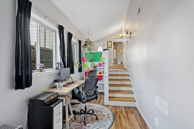 office area featuring lofted ceiling, visible vents, baseboards, and wood finished floors