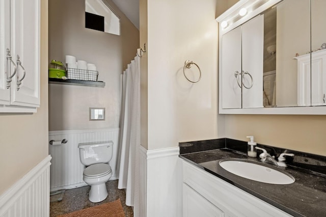 full bath featuring a wainscoted wall, vanity, and toilet