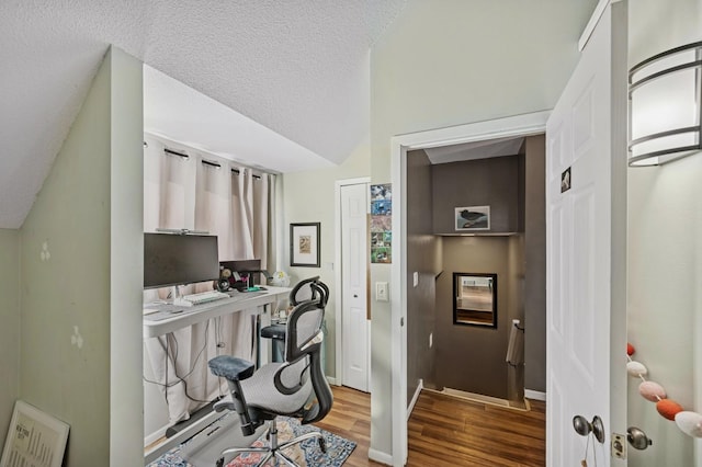 office area featuring a textured ceiling, baseboards, wood finished floors, and lofted ceiling