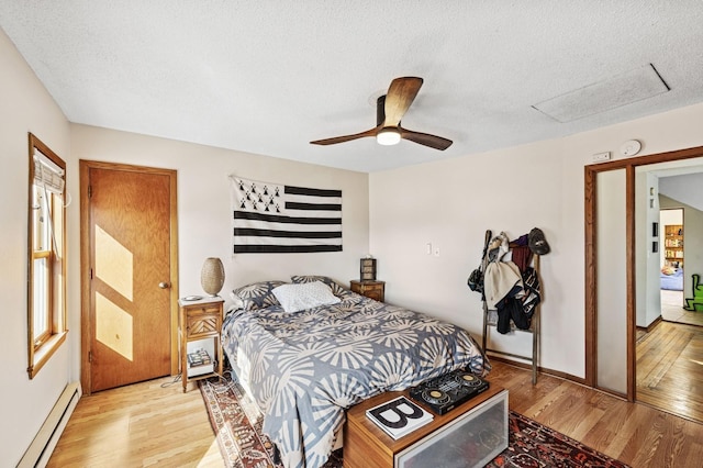 bedroom featuring a textured ceiling, ceiling fan, baseboards, baseboard heating, and light wood finished floors