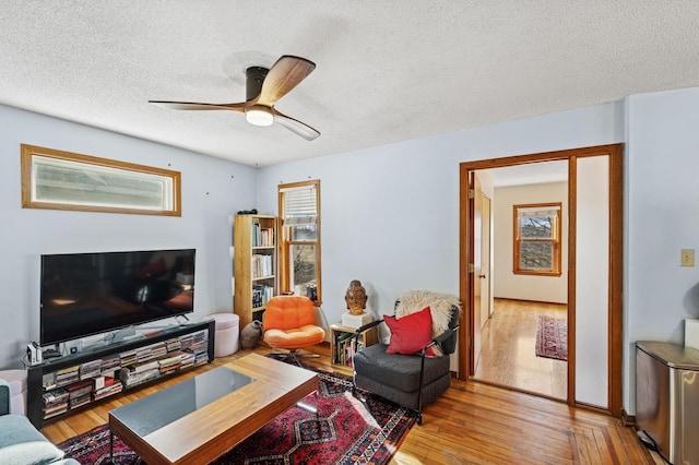 living area featuring a textured ceiling, a ceiling fan, and light wood-style floors