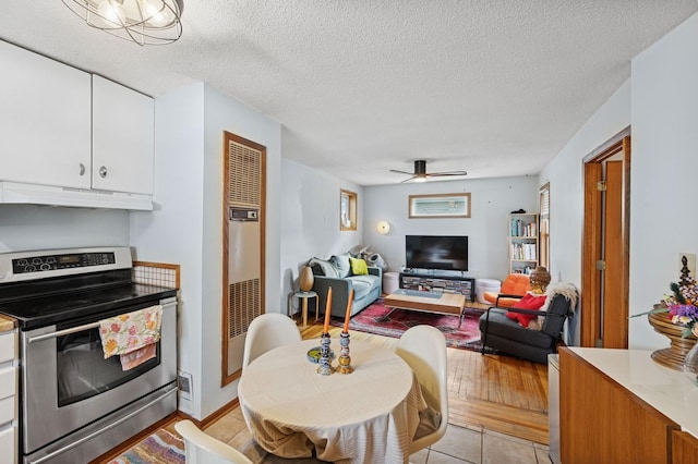 living room featuring a textured ceiling, ceiling fan, and light wood-type flooring