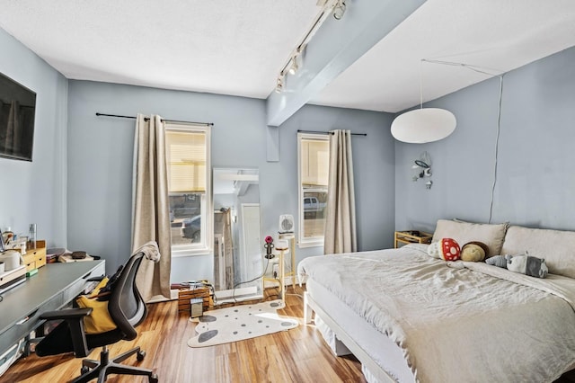 bedroom with track lighting and wood finished floors