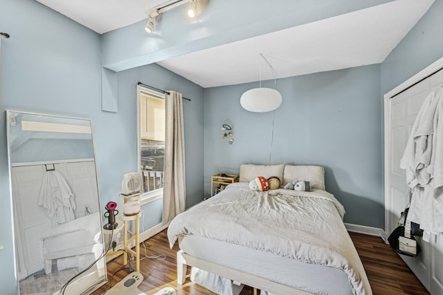 bedroom with rail lighting, baseboards, and wood finished floors