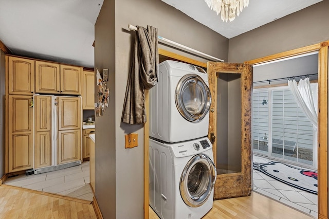 laundry room with stacked washer and dryer, a notable chandelier, laundry area, and light wood-style floors