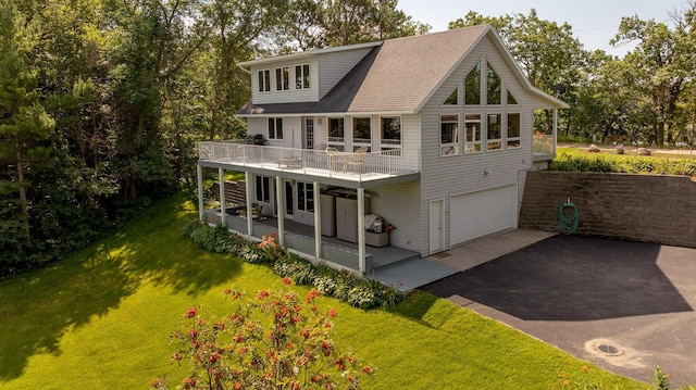 back of property with a lawn, driveway, and an attached garage