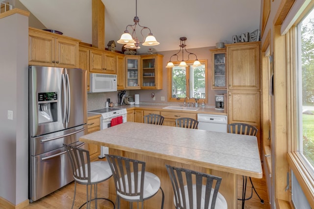 kitchen with glass insert cabinets, white appliances, light countertops, and hanging light fixtures