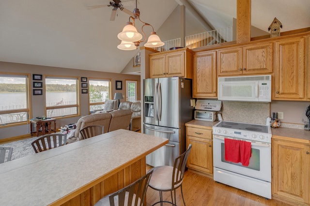 kitchen with white appliances, a kitchen bar, open floor plan, and light countertops