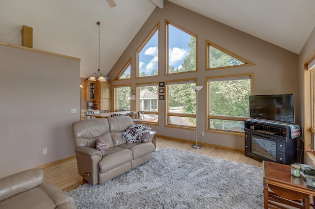 living room featuring high vaulted ceiling, light wood-style flooring, and baseboards