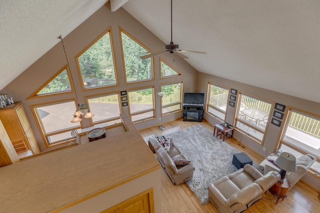 living room with a ceiling fan, light wood-style flooring, beamed ceiling, a textured ceiling, and high vaulted ceiling