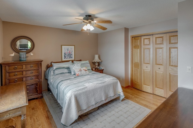 bedroom featuring ceiling fan, a closet, light wood-type flooring, and a textured ceiling