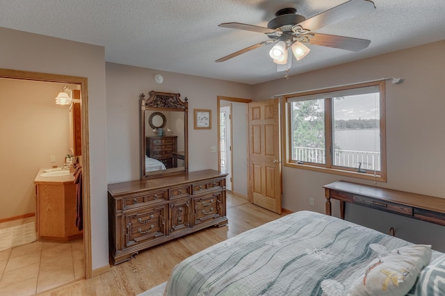 bedroom with a textured ceiling, ceiling fan, a sink, and light wood-style floors