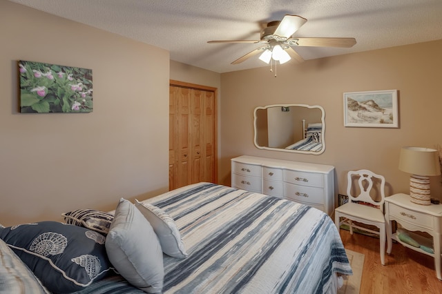 bedroom with light wood finished floors, ceiling fan, a textured ceiling, and a closet