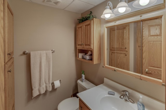 half bath featuring visible vents, vanity, and toilet