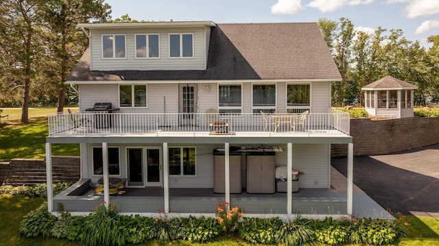 rear view of house featuring a shingled roof, a balcony, and a wooden deck