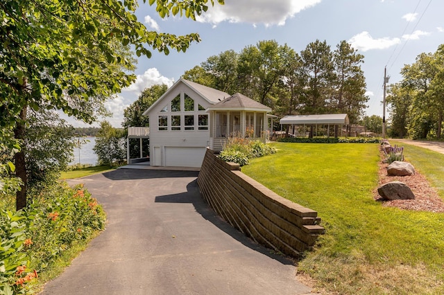 view of front of home with aphalt driveway, a front lawn, an attached garage, and a sunroom