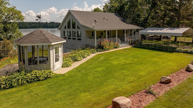 rear view of house with covered porch, a water view, and a lawn