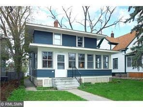 view of front of home with a chimney, a front yard, and a sunroom