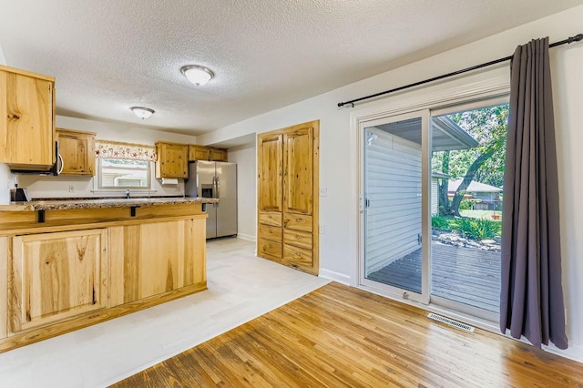 11570 Juniper St NW, Coon Rapids, MN 55448 - kitchen with a textured ceiling, light wood finished floors, stainless steel refrigerator with ice dispenser, a peninsula, and light countertops