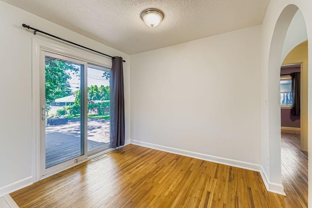 11570 Juniper St NW, Coon Rapids, MN 55448 - empty room featuring light wood-style floors, arched walkways, and a textured ceiling