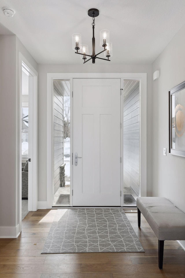 foyer entrance featuring a notable chandelier, baseboards, and hardwood / wood-style flooring