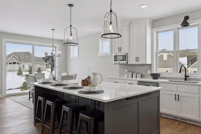 kitchen with light countertops, a center island, white cabinets, and a sink