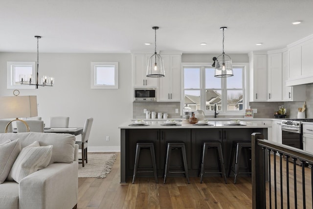 kitchen featuring white cabinets, stainless steel appliances, a kitchen bar, and light countertops