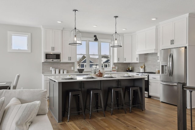 kitchen featuring white cabinetry, appliances with stainless steel finishes, light countertops, and a center island