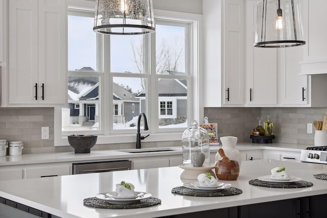 kitchen with light countertops, a healthy amount of sunlight, a sink, and white cabinets