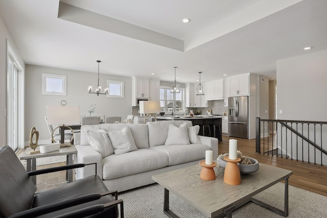 living area featuring light wood-type flooring, a notable chandelier, and recessed lighting