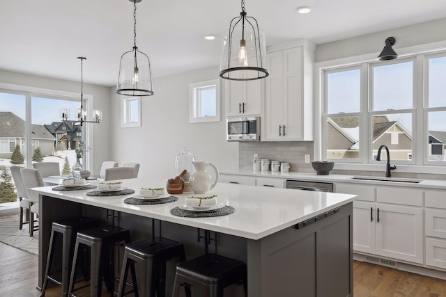 kitchen with a kitchen breakfast bar, stainless steel appliances, light countertops, white cabinetry, and a sink