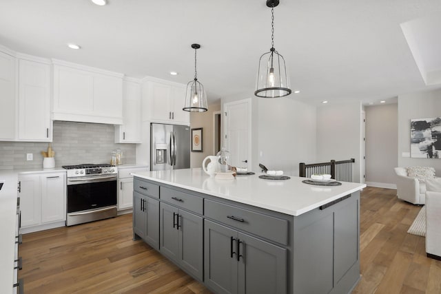 kitchen featuring an island with sink, stainless steel appliances, light countertops, and gray cabinetry