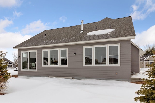 snow covered property featuring roof with shingles