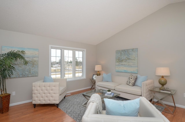 living area featuring vaulted ceiling, baseboards, and wood finished floors