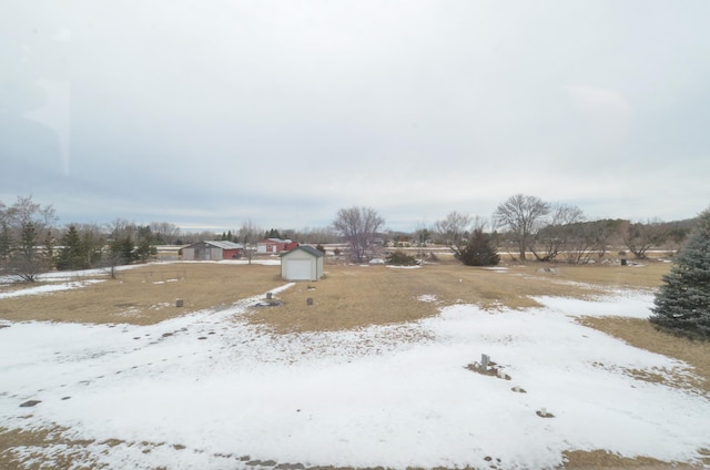 yard layered in snow with a garage, a storage unit, and an outdoor structure