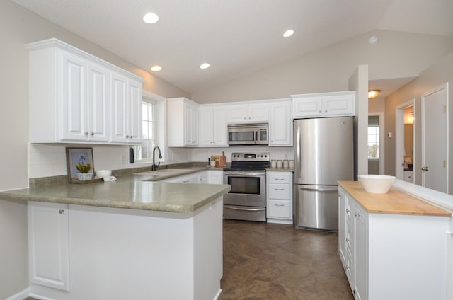 kitchen featuring appliances with stainless steel finishes, lofted ceiling, white cabinetry, and a sink