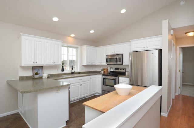 kitchen with lofted ceiling, stainless steel appliances, a sink, and white cabinetry