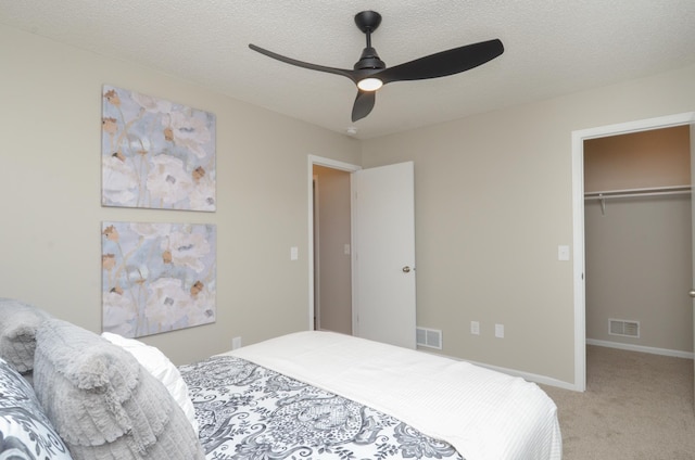 bedroom featuring a textured ceiling, a spacious closet, visible vents, and light colored carpet