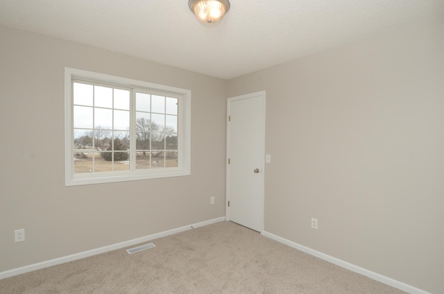 empty room with visible vents, a textured ceiling, baseboards, and carpet flooring