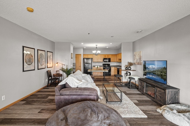 living area with a chandelier, dark wood-type flooring, a textured ceiling, and baseboards