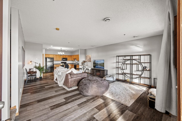 living area featuring an inviting chandelier, a textured ceiling, baseboards, and wood finished floors