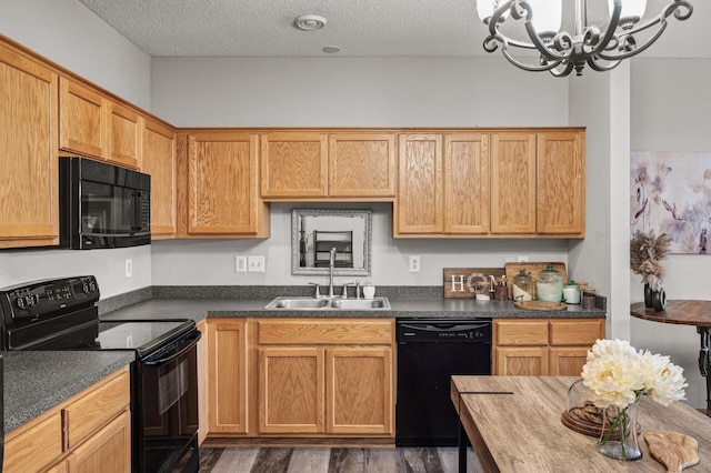 kitchen featuring dark wood-style flooring, an inviting chandelier, a sink, a textured ceiling, and black appliances